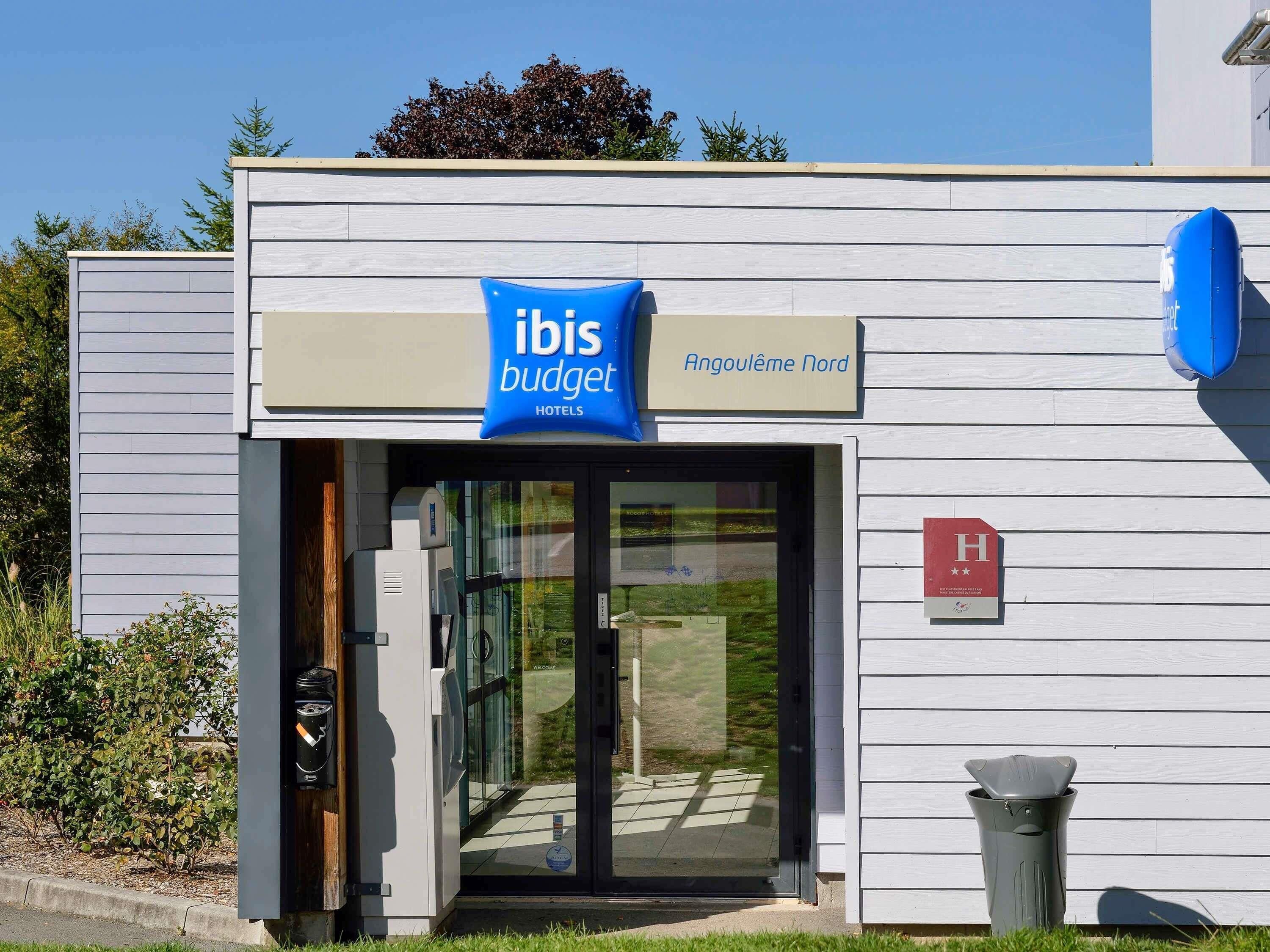 Entrada d'un hotel modern amb un cartell que indica 'ibis budget' i 'Angoulême Nord' com a localització.