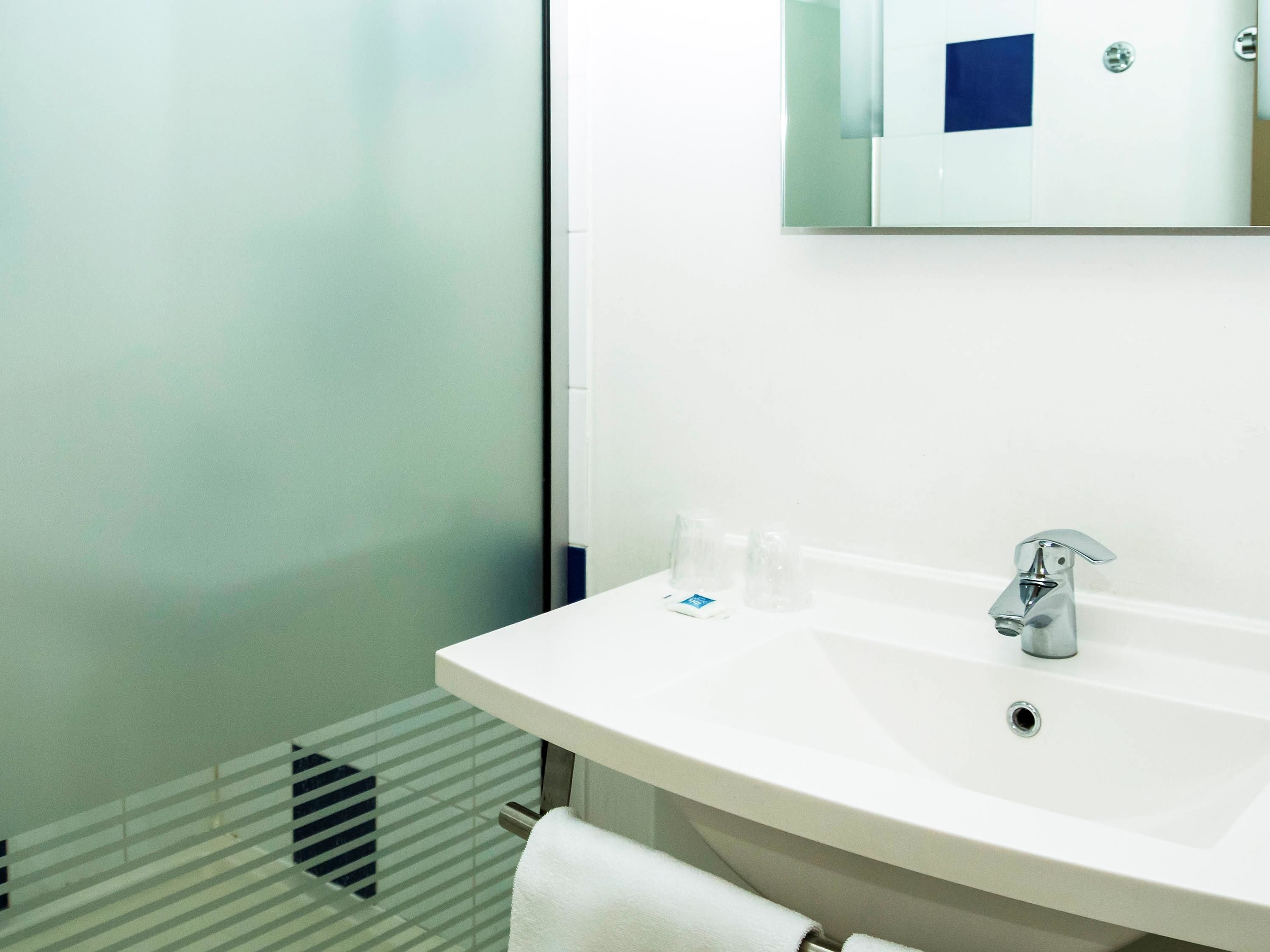 A modern bathroom with a white sink, a mirror, and a towel rack.