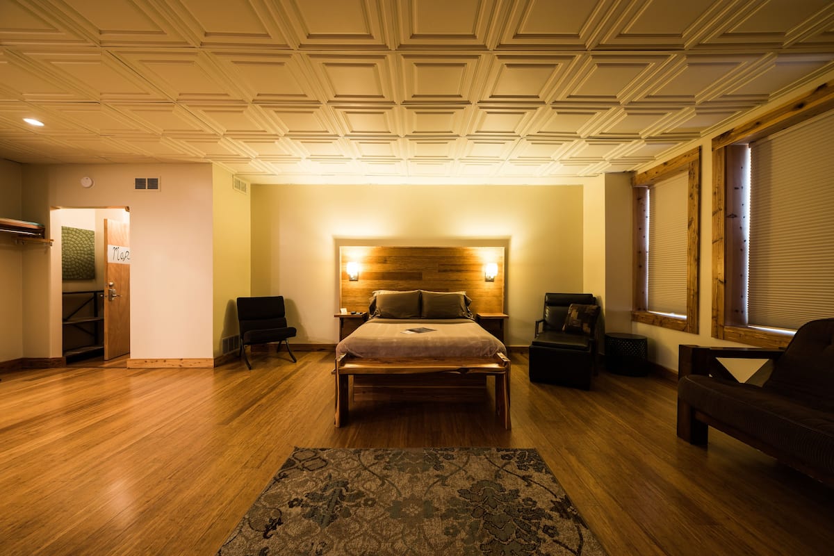 A spacious bedroom with a large bed, a wooden headboard, two bedside tables, and a nightstand.