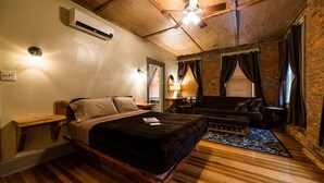 Une chambre à coucher avec un lit en bois, un ventilateur de plafond, un bureau et un canapé.