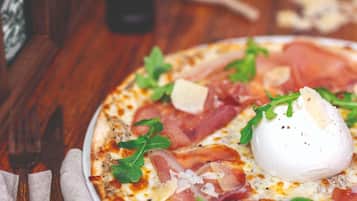 A pizza with toppings and a poached egg on a wooden table.