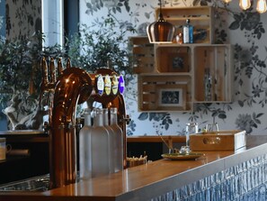A bar area with a beer tap, a counter, and a decorative plant in the background. - ibis budget Sens (Sens)