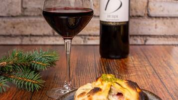 Una copa de vino tinto, una botella con etiqueta y un plato de comida sobre una mesa de madera.
