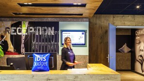 A reception area with a wooden ceiling, a digital display, and a blue 'ibis budget hotels' sign. - ibis budget Sens (Sens)