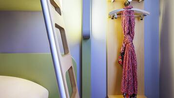 Een stapelbed met een houten trap, een ophangrek met een geruit kledingstuk en een houten plankunit.