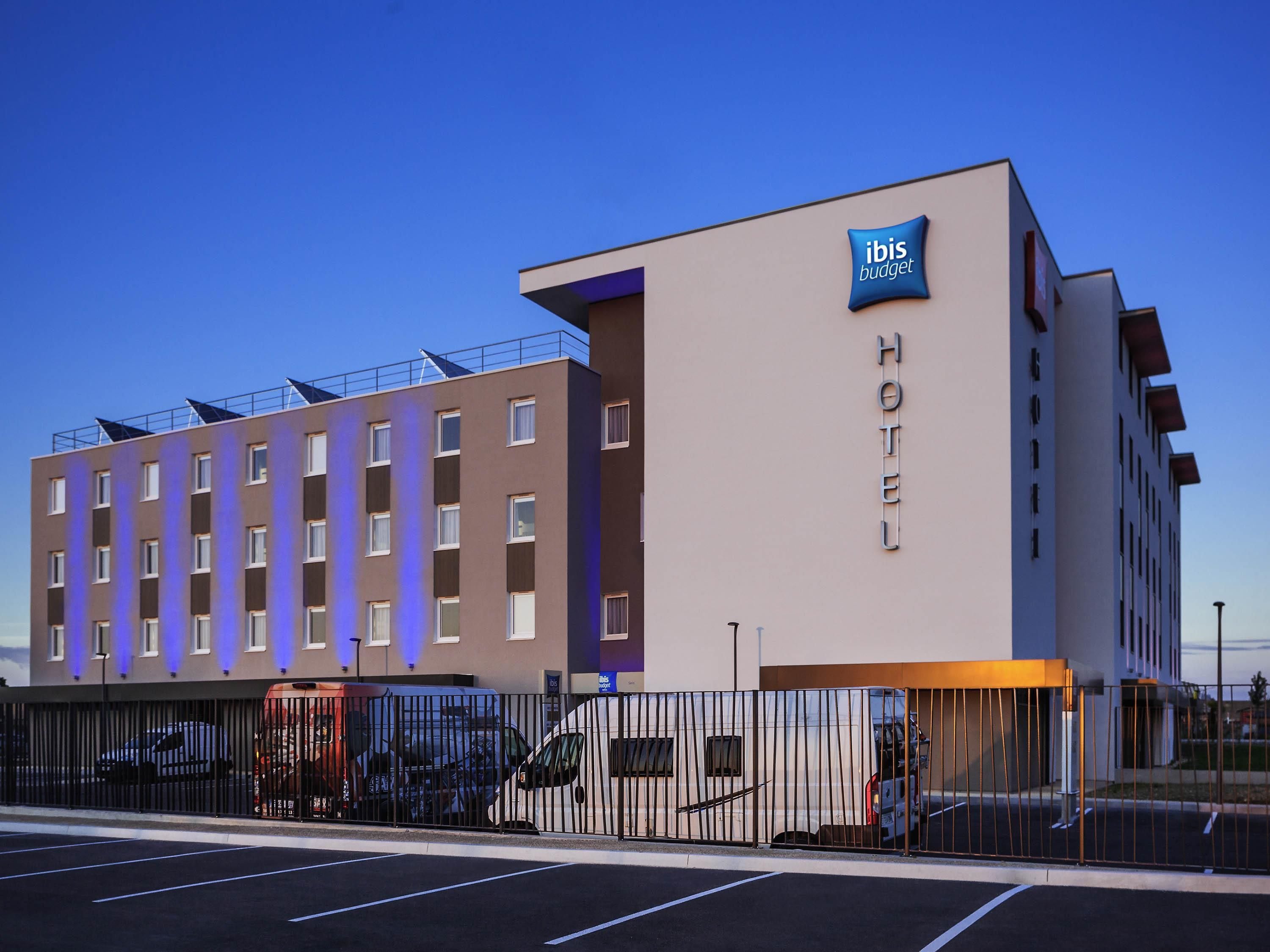 A modern hotel building with a sign indicating it's an ibis budget hotel.