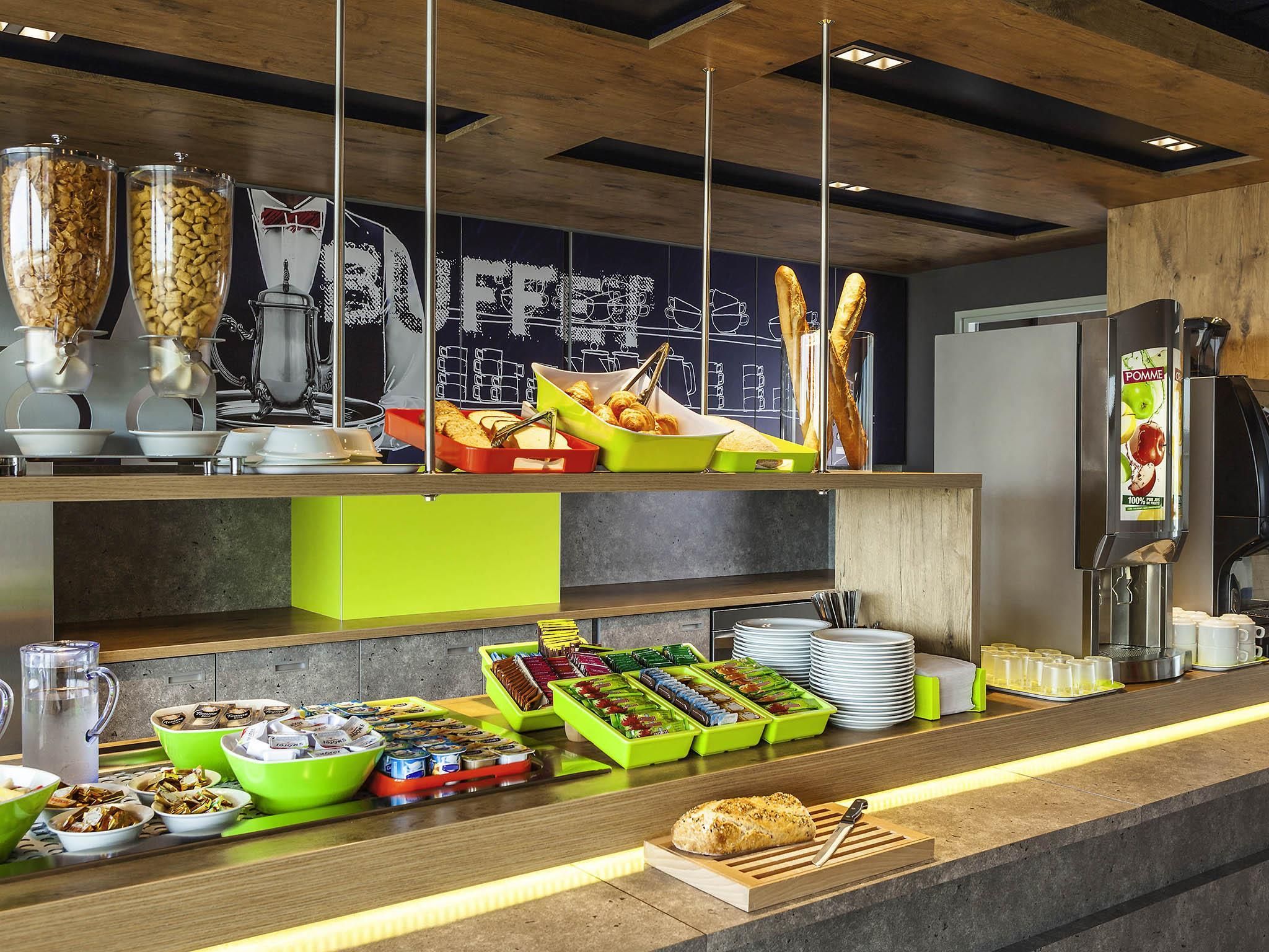 A buffet setup with various food items, a coffee machine, and a refrigerator.