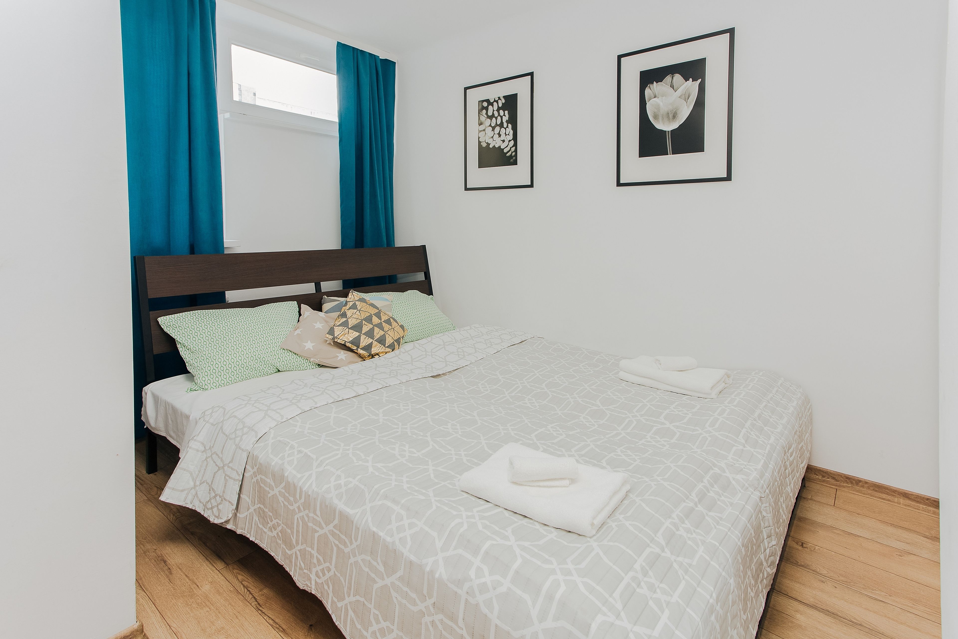 A neatly made bed with a patterned bedspread, a pillow with a geometric design, and a folded towel on the bed.