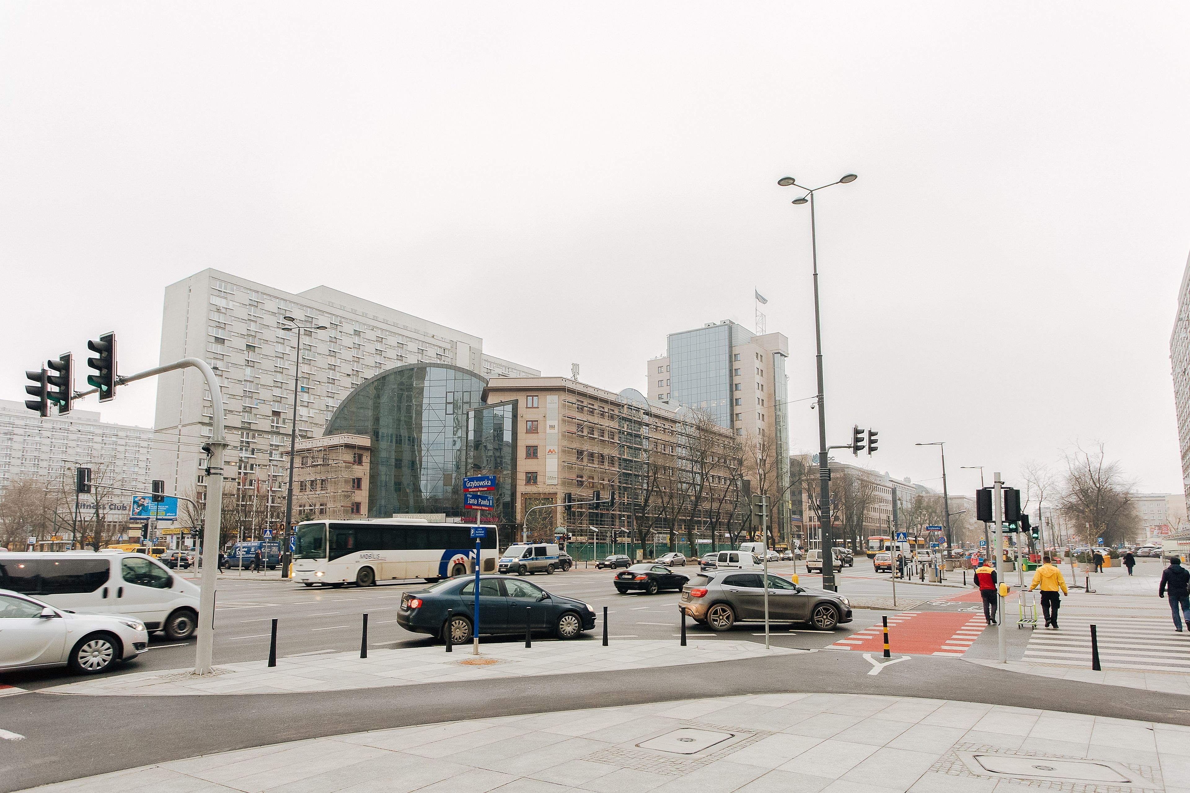 A city intersection with modern buildings, a bus, and cars.