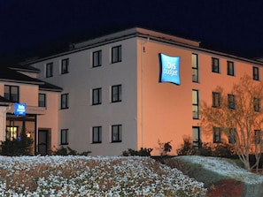 Een hotel met een bord waarop 'Ibis Budget' staat en meerdere ramen.
