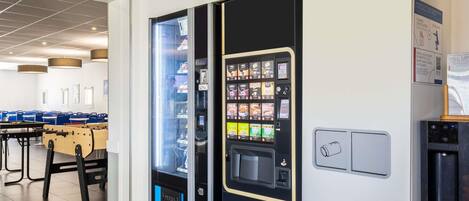 Zona de máquinas expendedoras con una cafetera y dispensador de bebidas.