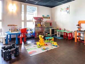 Een speelkamer met een kasteel, stoelen en allerlei speelgoed.