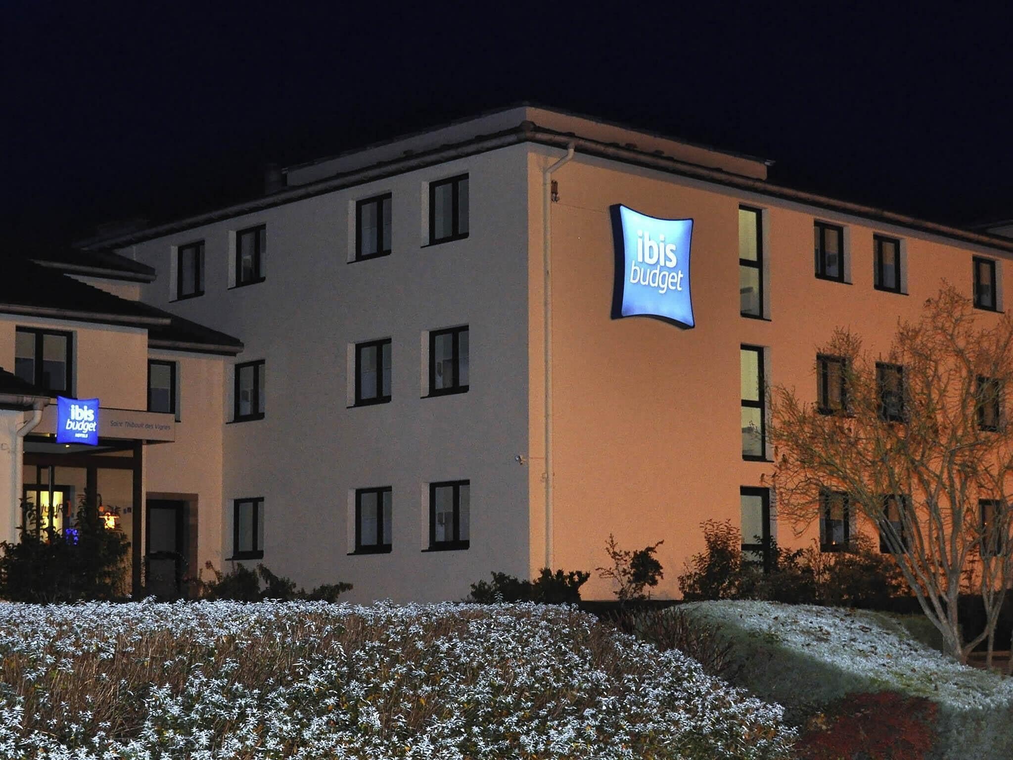 A multi-story hotel building with a prominent 'Ibis Budget' sign on the facade.