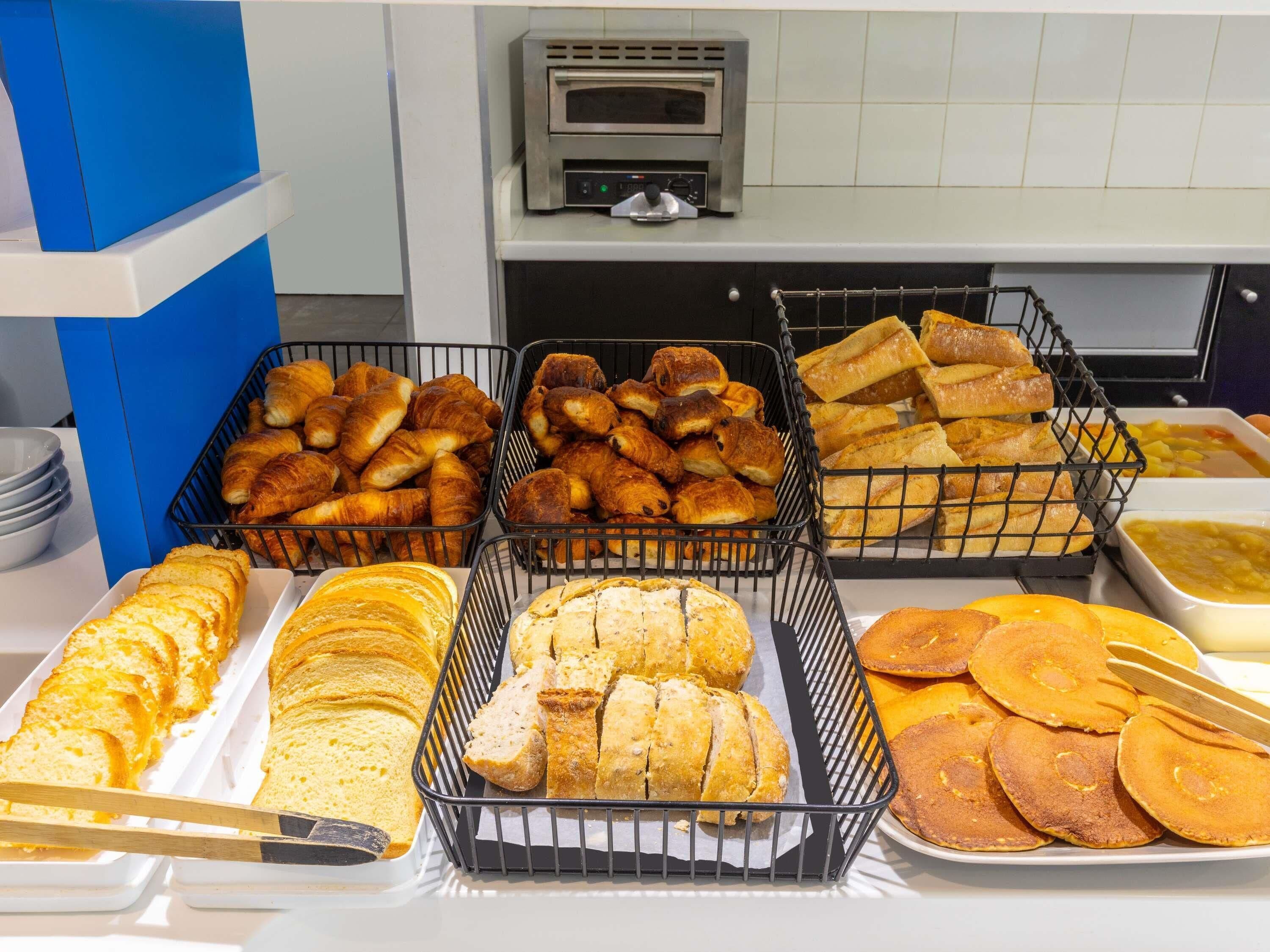 Un bufé de desayuno con diferentes tipos de pan y un horno tostador al fondo.
