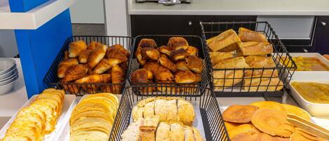 Un bufé de desayuno con diferentes tipos de pan y un horno tostador al fondo.