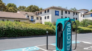 An electric vehicle charging station in a parking lot with a building in the background.