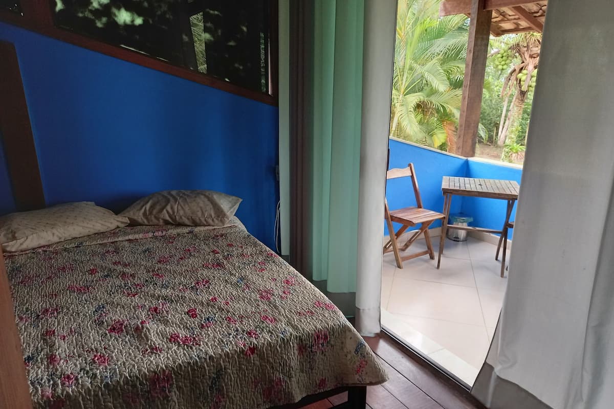 A bedroom with a bed, a wooden chair, and a table.