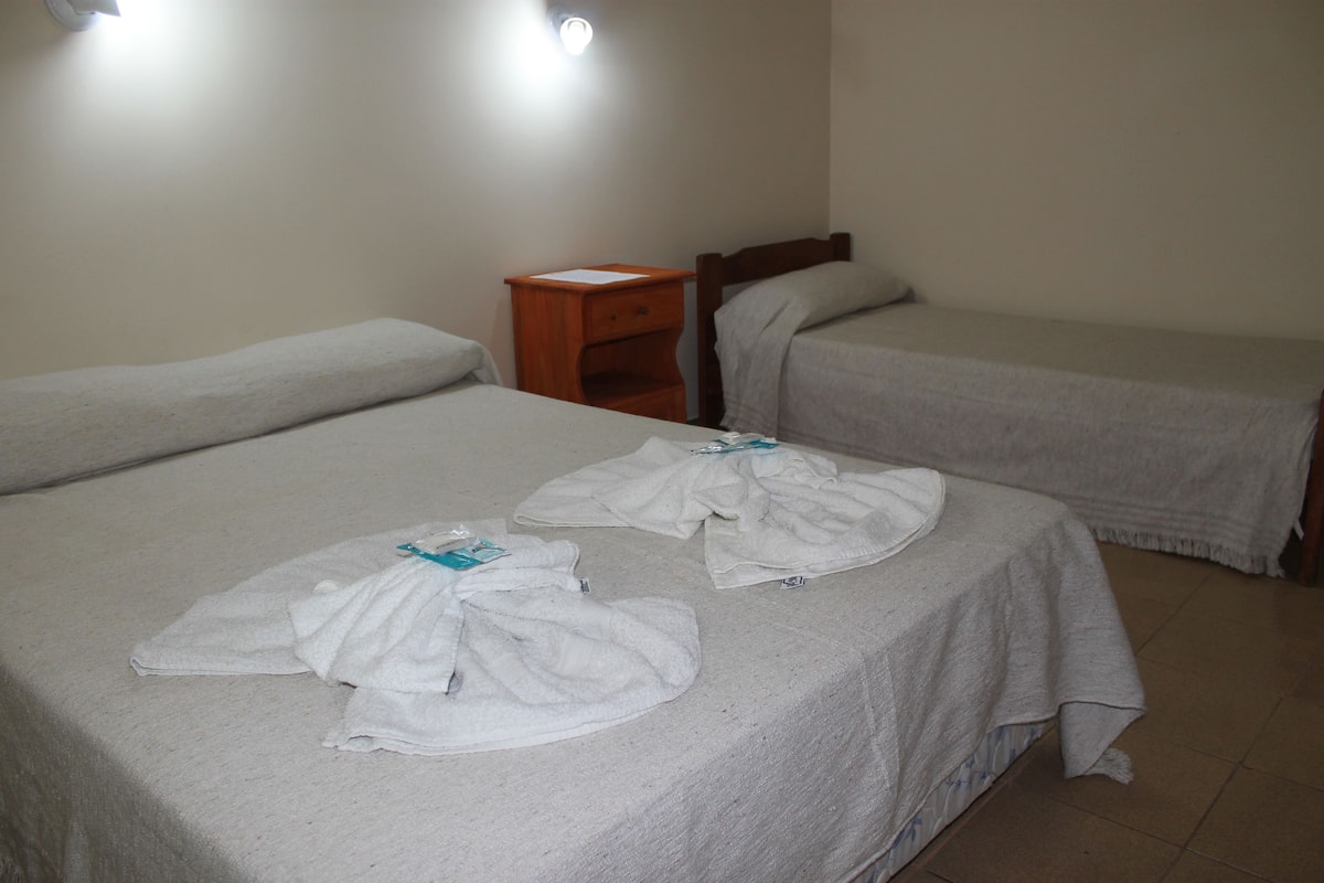 A hotel room with two single beds, a wooden nightstand, and a small drawer unit.