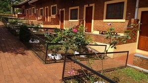 A brick building with multiple windows and doors, surrounded by a brick pathway and a metal fence. - Nuevo Raices Apart (Puerto Iguazú)