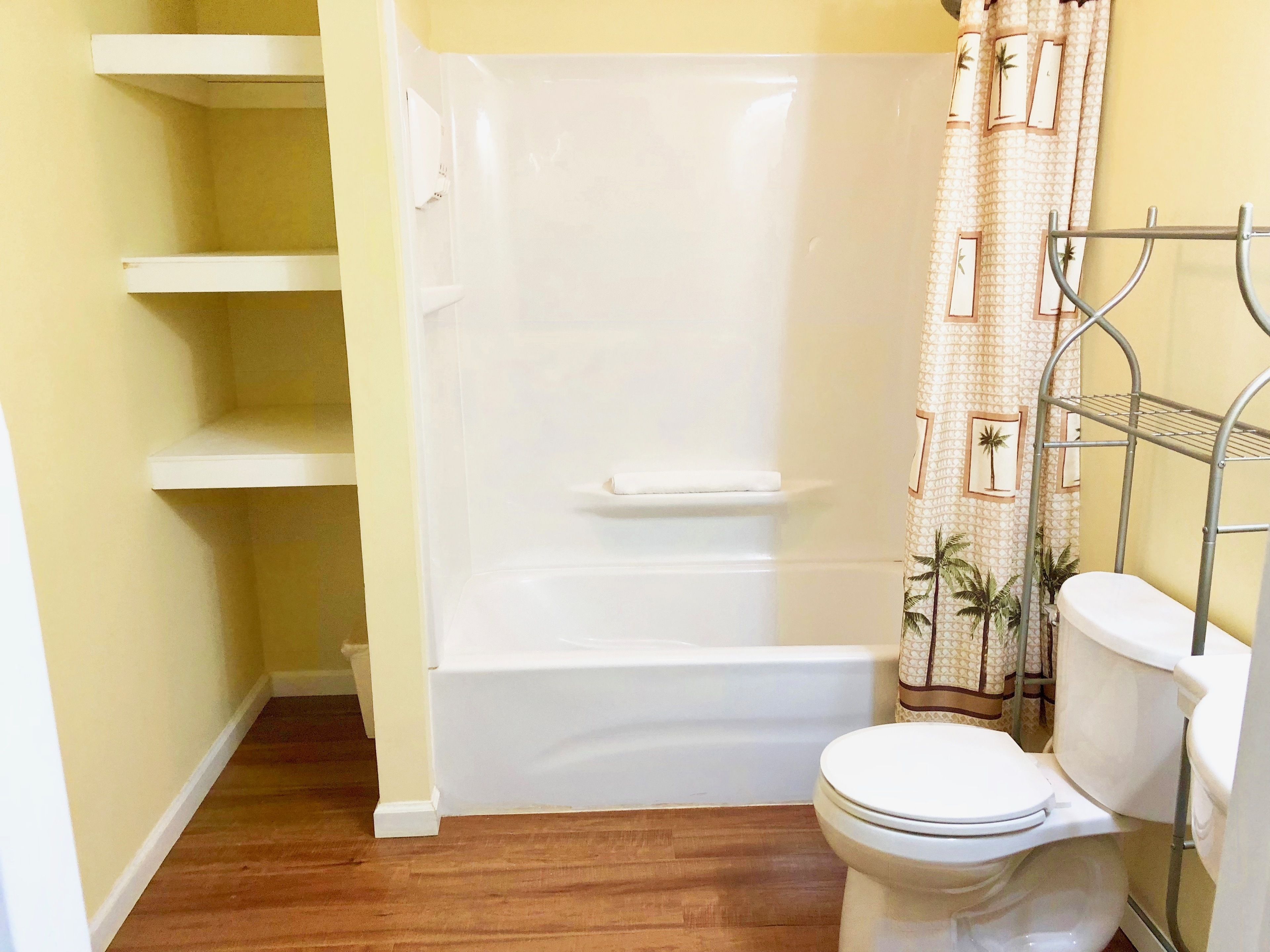 Une salle de bain avec une baignoire, des toilettes et des étagères.