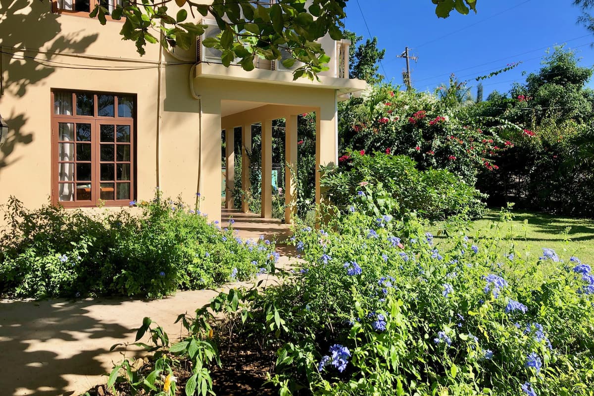 A building with a garden in front, featuring a variety of plants and flowers.