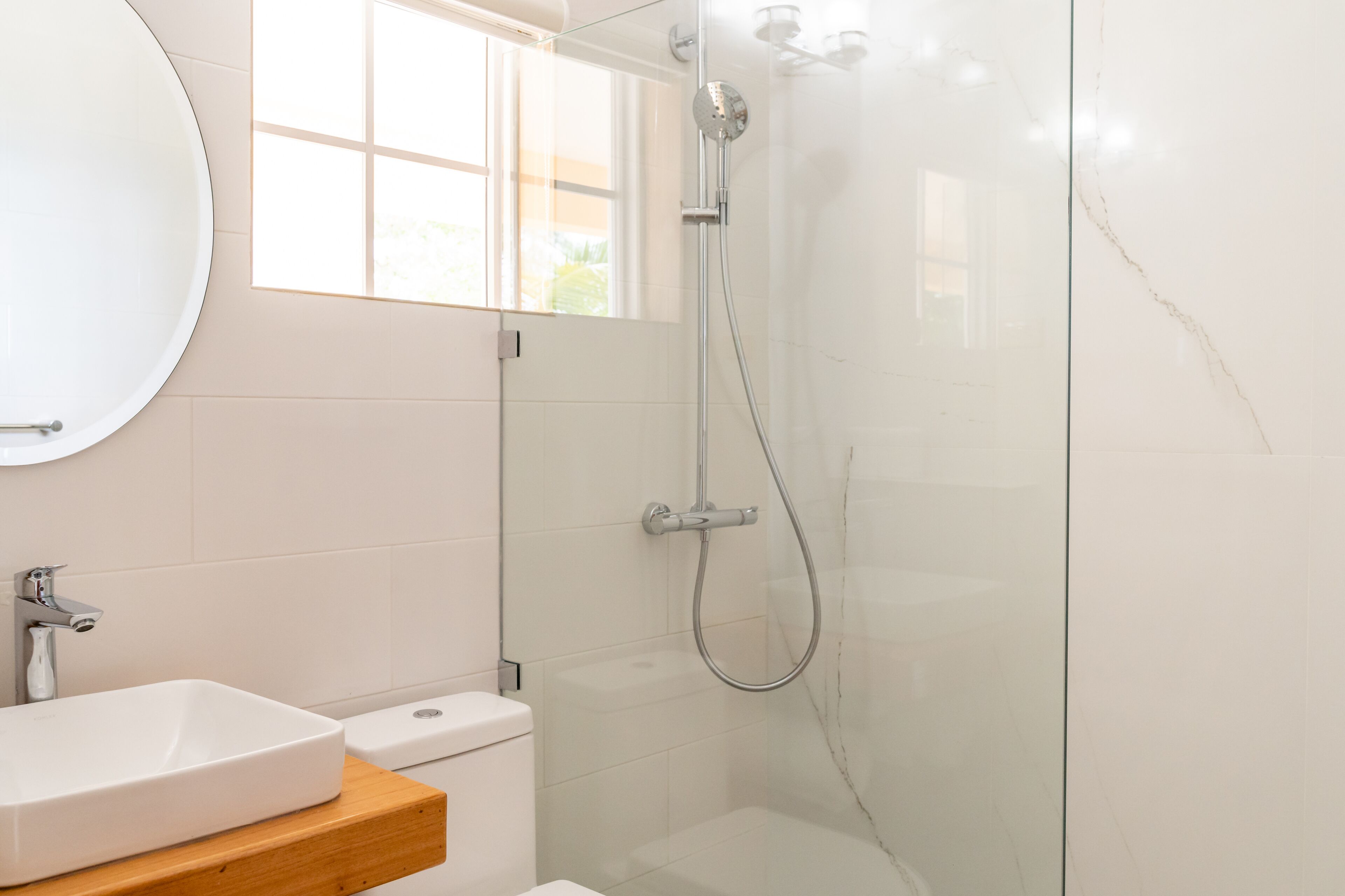 Een moderne badkamer met een wit wastafelmeubel, toilet en douche.