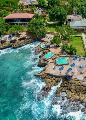 Un resort costero con varias piscinas, zonas de descanso y un litoral rocoso.