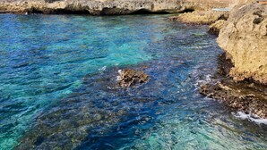 A coastal area with clear blue water, a stone bridge, and a building with a red roof. - The Westender Inn (Negril)
