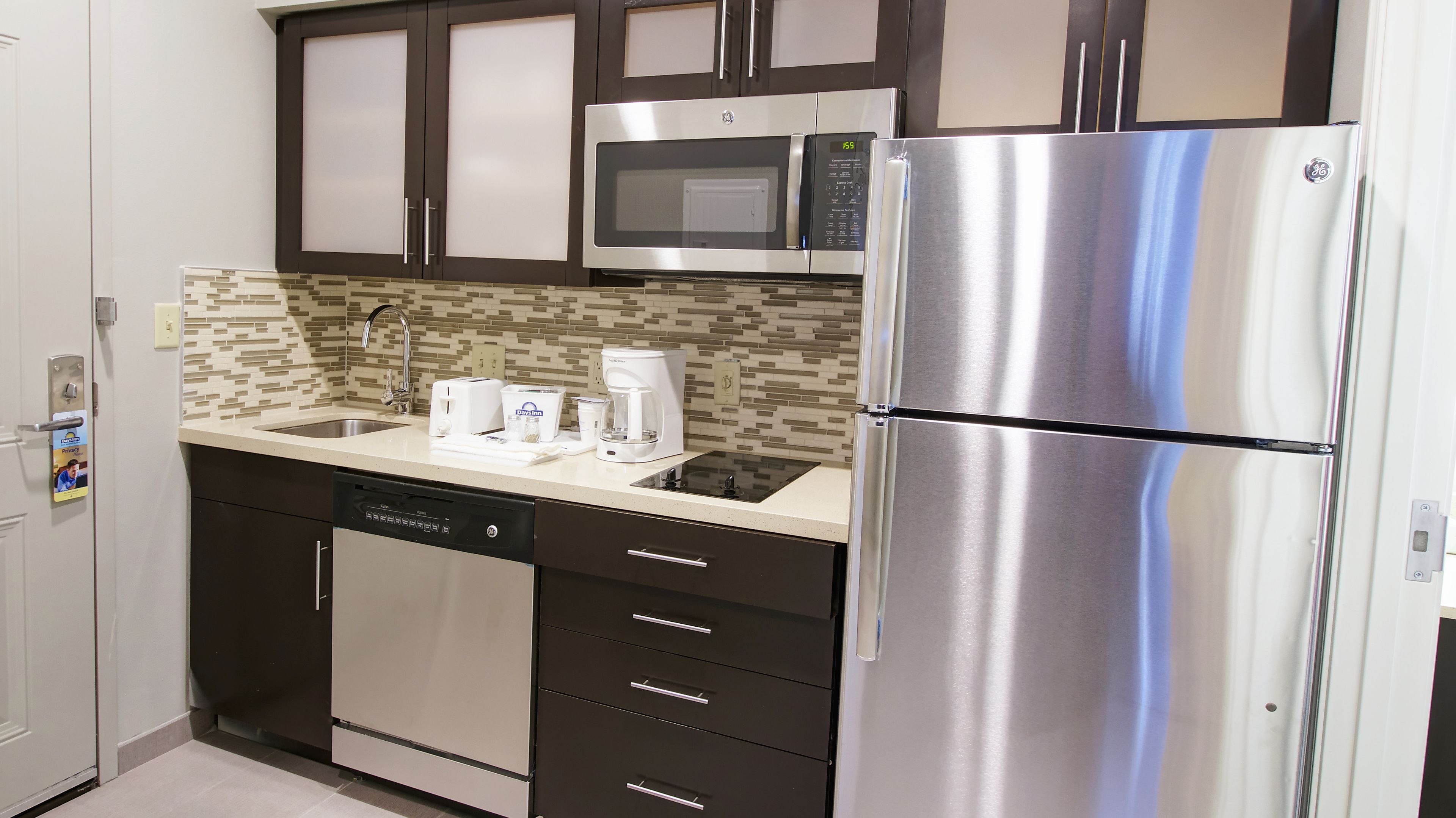 Cocina compacta equipada con lavavajillas, microondas y refrigerador de acero inoxidable.
