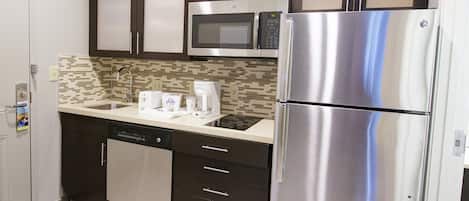 Cocina compacta equipada con lavavajillas, microondas y refrigerador de acero inoxidable.