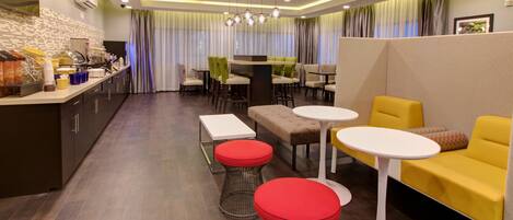 Una hall d'hotel moderna con zona ristoro, posti a sedere e bancone della cucina.