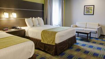 A hotel room with two beds, a sofa, a small table, and a painting on the wall.