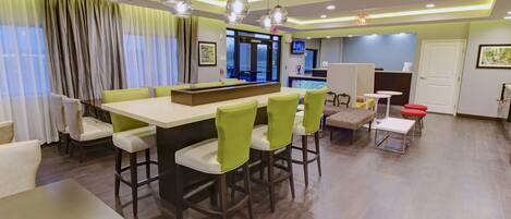A modern hotel lobby with a reception desk, bar area, and seating.