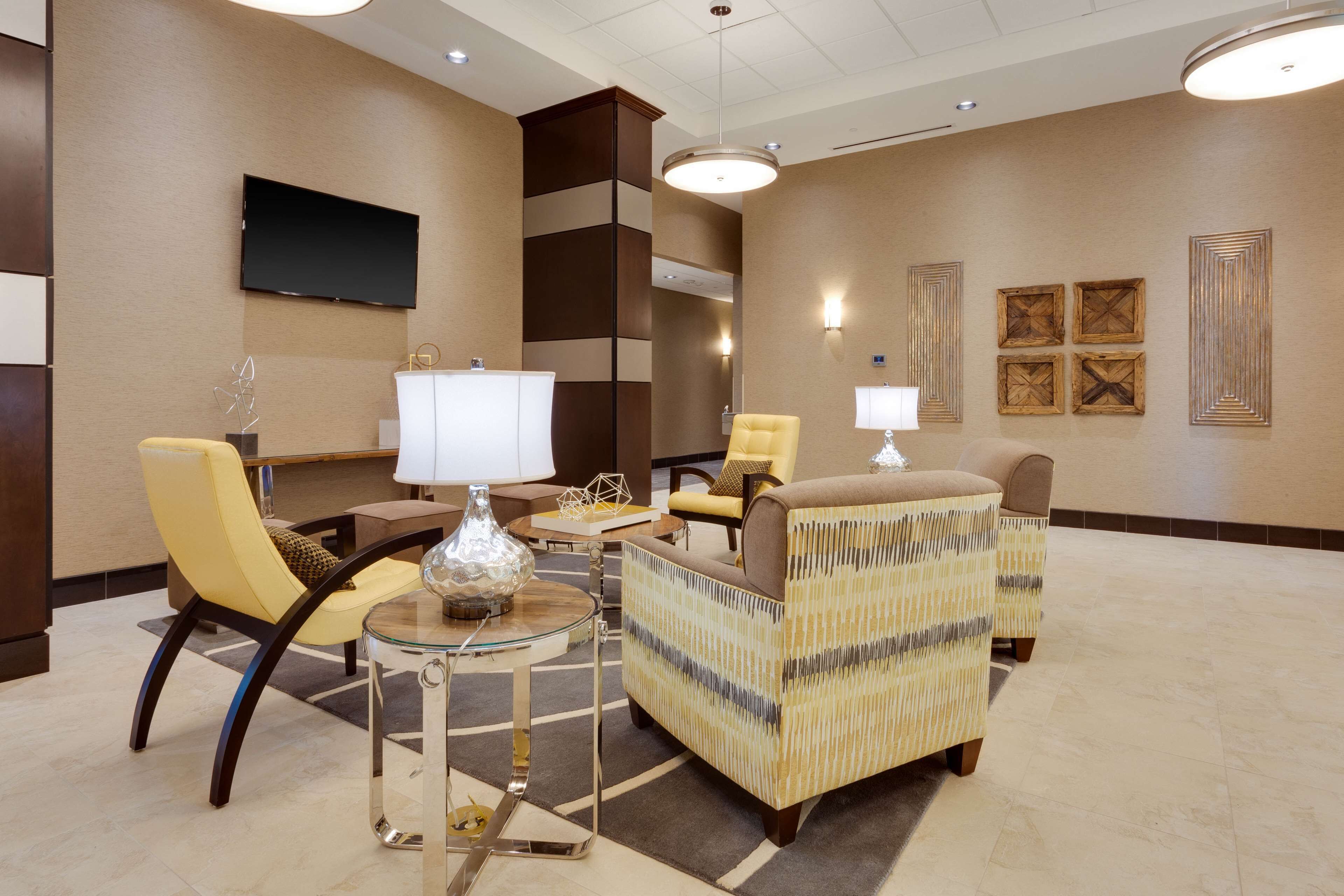 A modern lobby with a sofa set, a TV, and decorative wall art.