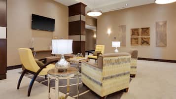 A modern lobby with a sofa set, a TV, and decorative wall art.