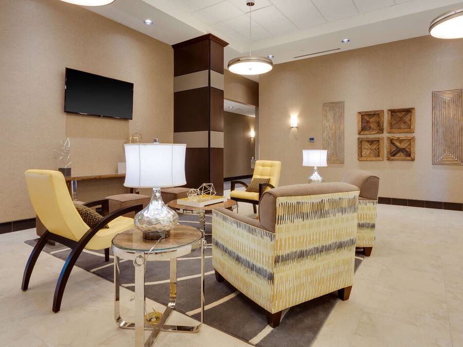 A modern lobby with a sofa set, a TV, and decorative wall art.