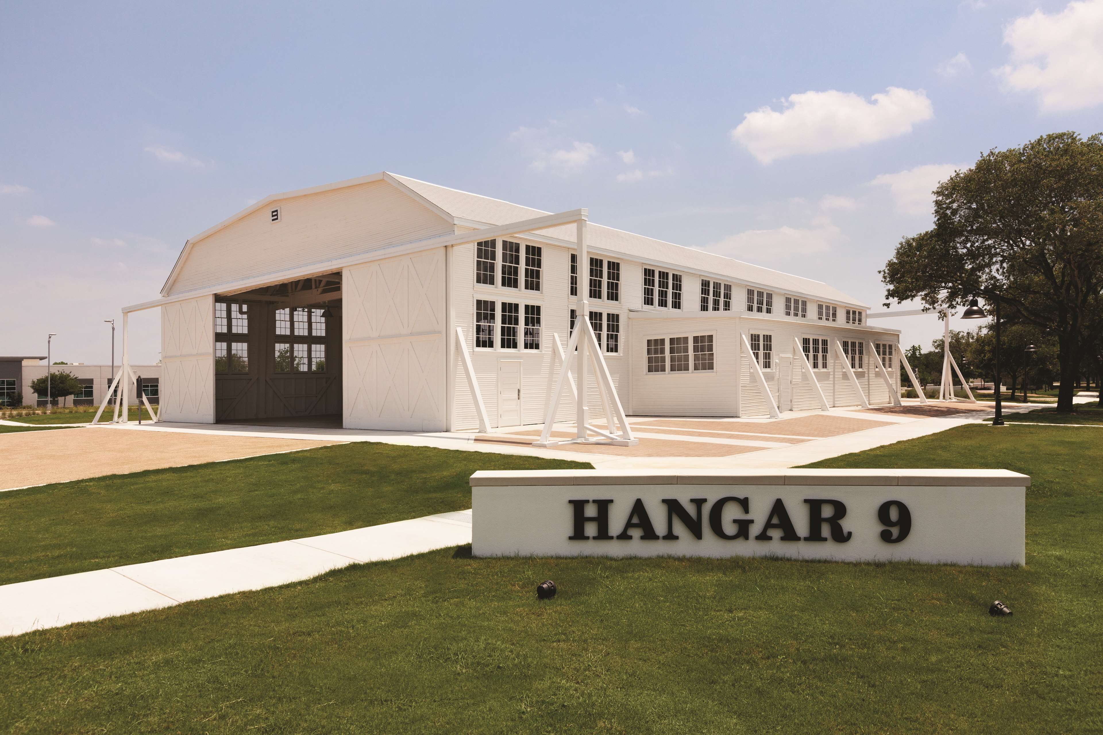 Een modern gebouw met een grote garagedeur en een bord waarop 'HANGAR 9' staat.