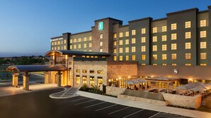 A hotel with a prominent 'Embassy Suites' sign, a brick facade, and a covered outdoor area with seating.