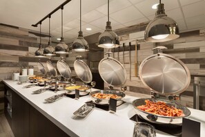 A buffet setup with multiple food stations and hanging pendant lights. - Embassy Suites by Hilton San Antonio Brooks Hotel & Spa (San Antonio)