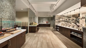 A modern kitchen with a long counter, glass display case, and various food items.