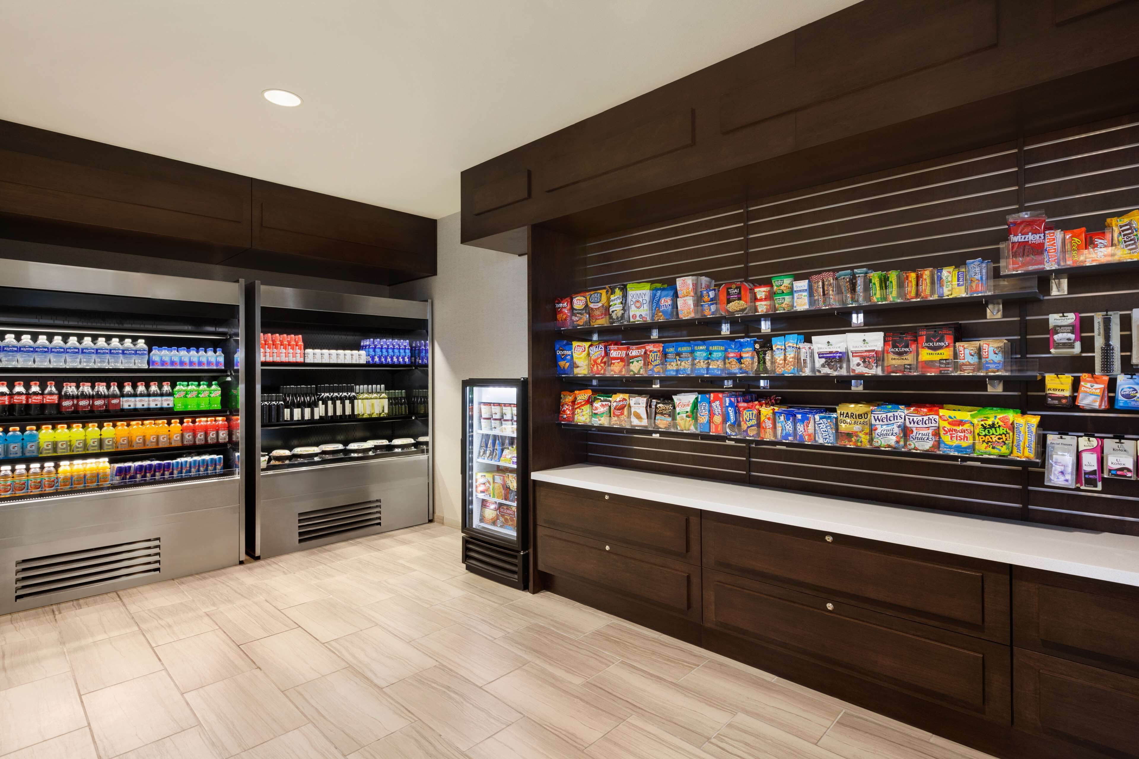 A well-lit snack and beverage area with refrigerated drinks and a variety of snack options on shelves.