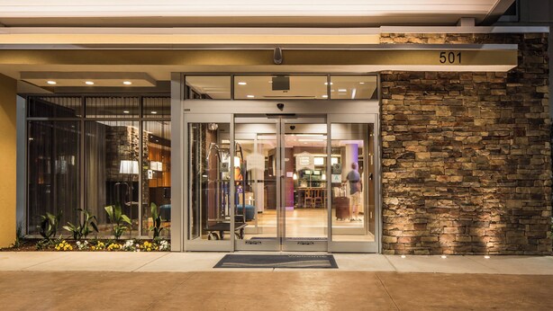 A hotel entrance with a stone facade, glass doors, and a number '501' above.
