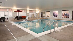 An indoor swimming pool with a tiled floor, a pool ladder, and a seating area with chairs and a table. - Hyatt Place Madison / Verona (Verona)