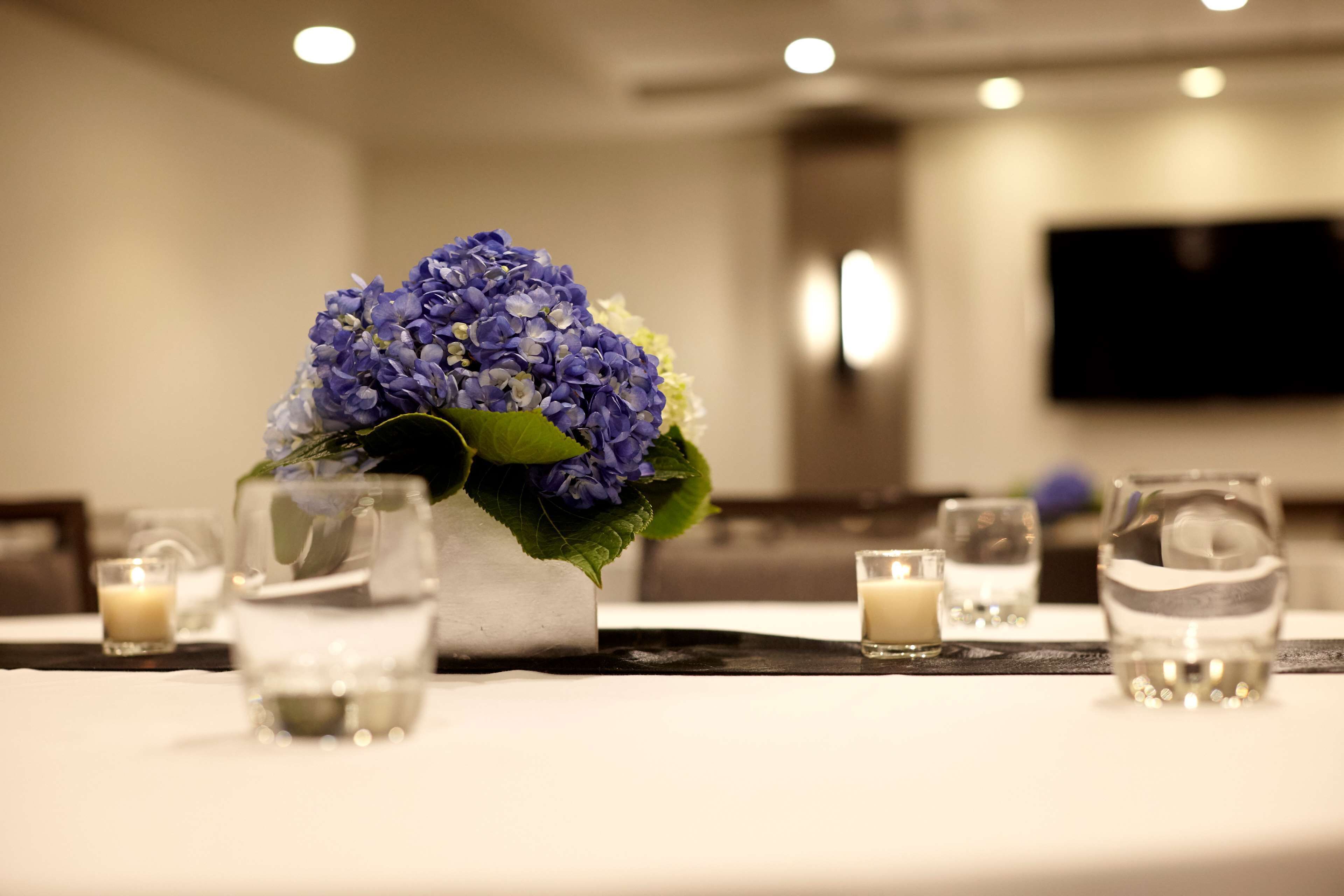 A table set with a vase of flowers, candles, and glasses.