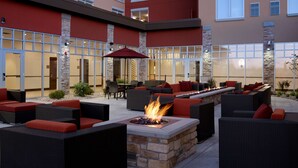 An outdoor patio with wicker furniture, a fire feature, and a stone wall. - Hyatt Place Madison / Verona (Verona)