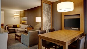 A modern hotel room with a wooden dining table, a sofa, and a TV mounted on the wall. - Hyatt Place Madison / Verona (Verona)