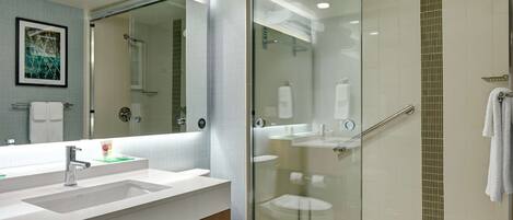 Et moderne badeværelse med en brusekabine i glas, en hvid vask og et toilet.