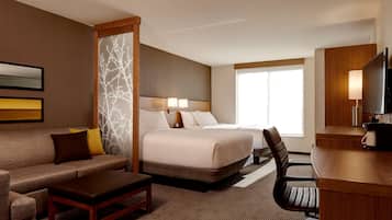 A hotel room with a bed, a sofa, a desk, and a TV.