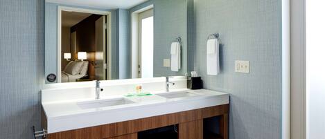 A modern bathroom with a double sink vanity, a large mirror, and a towel rack.