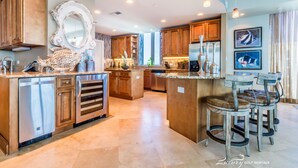A spacious kitchen with wooden cabinets, a central island, and bar stools.